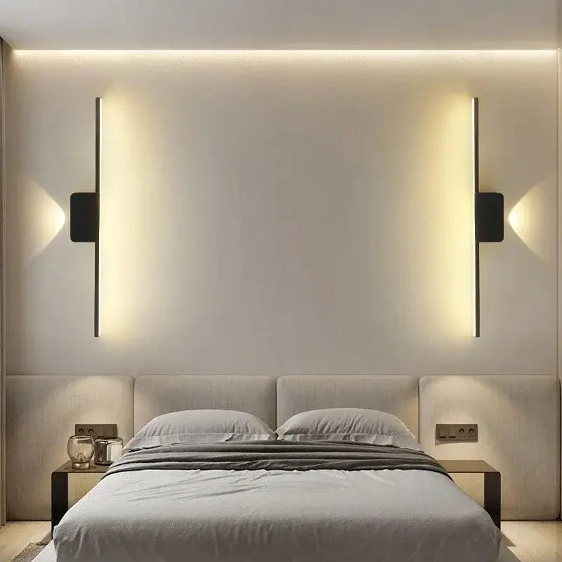 Two minimal wall lights placed above the bed in a bedroom setting.
