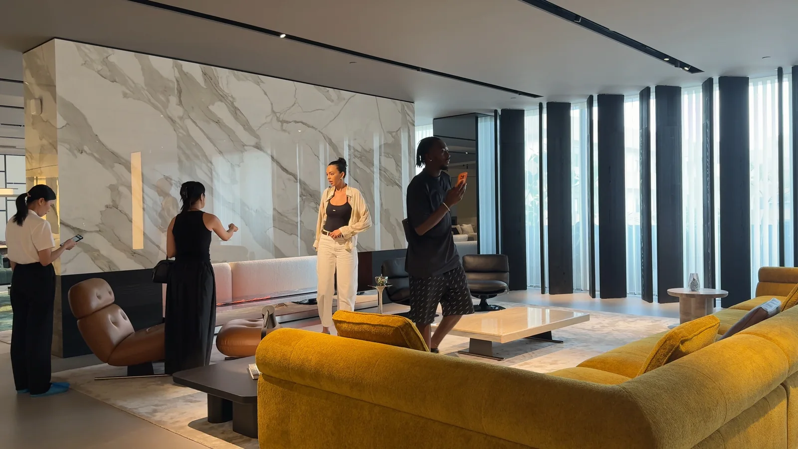 A woman in a black dress discusses showroom selections with two visitors.