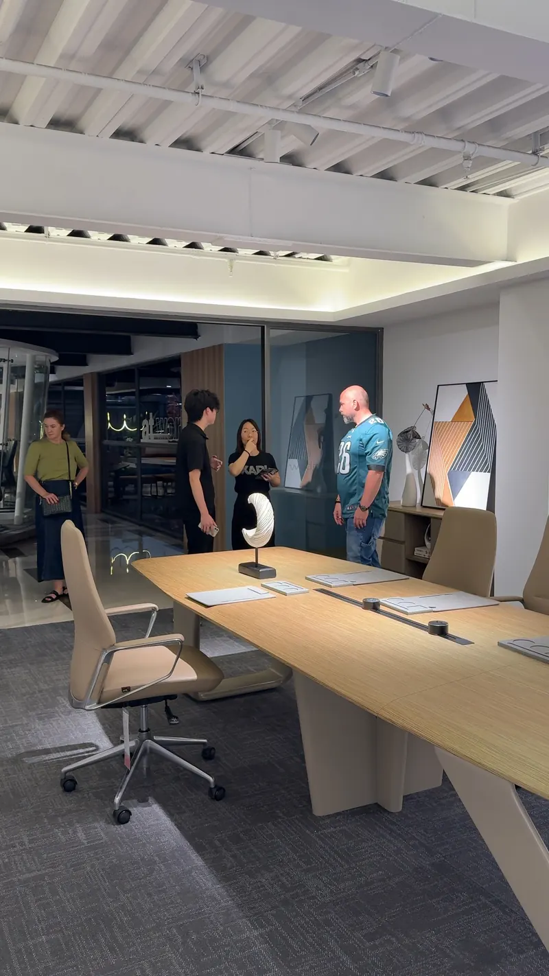Four adults stand behind a large timber desk with office chairs in the foreground.