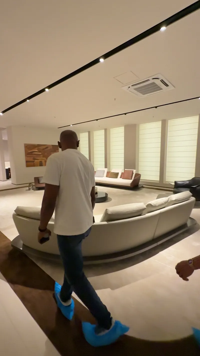 A person walks beside a curved sofa arrangement in a showroom.