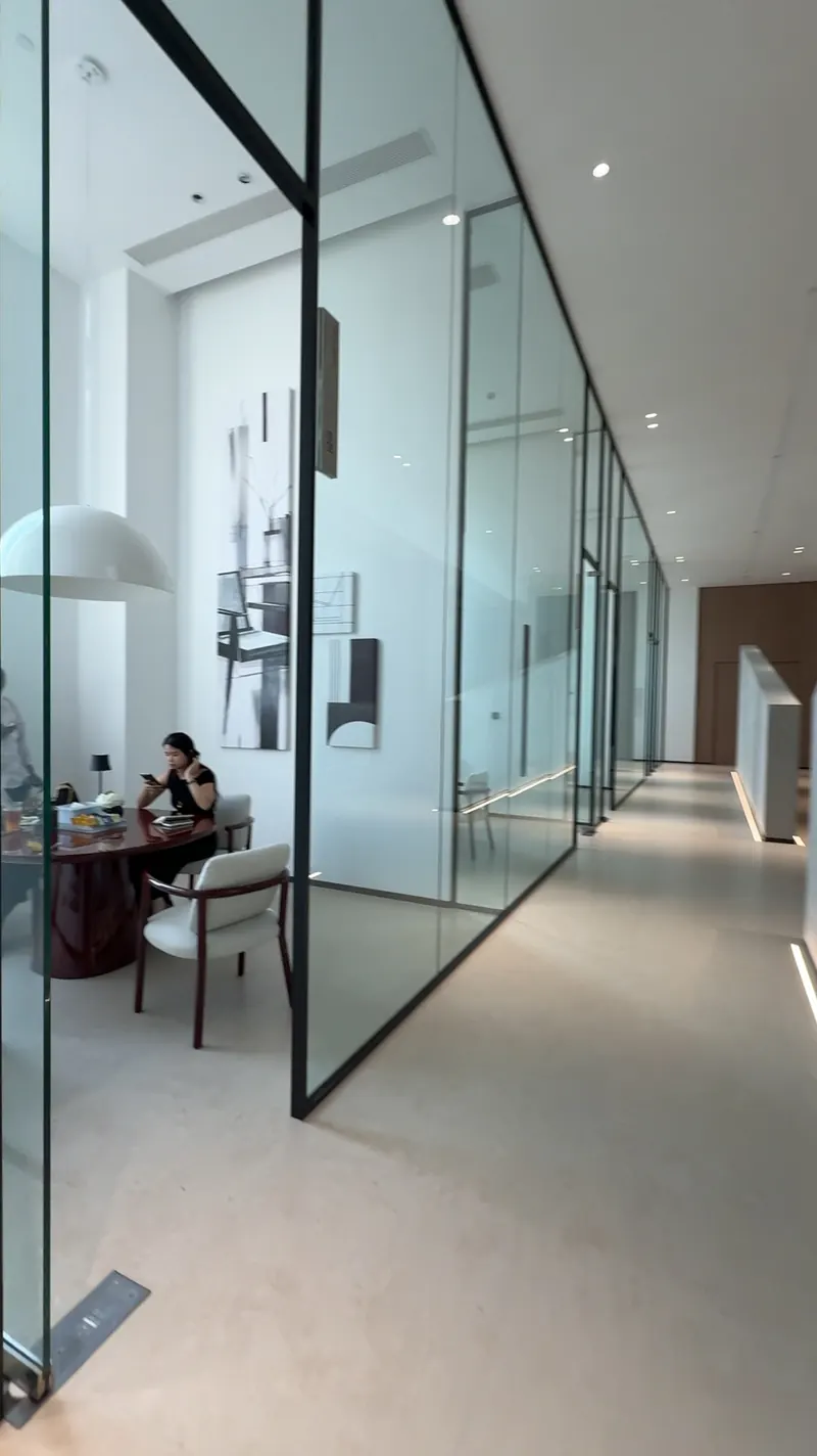 A glass-sided meeting room with a round table and a person seated inside.
