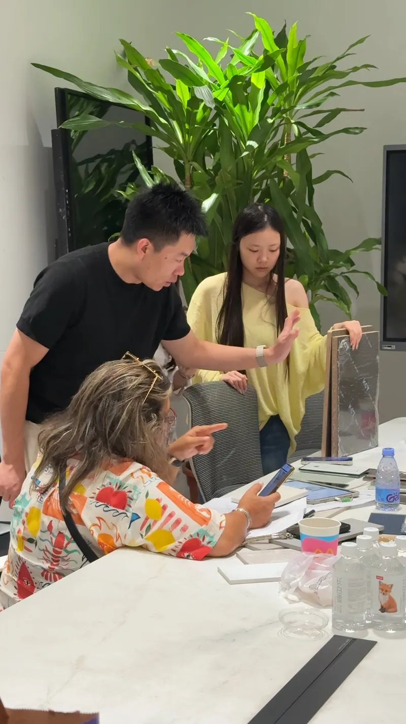 People point toward upright patterned finish boards on a table.