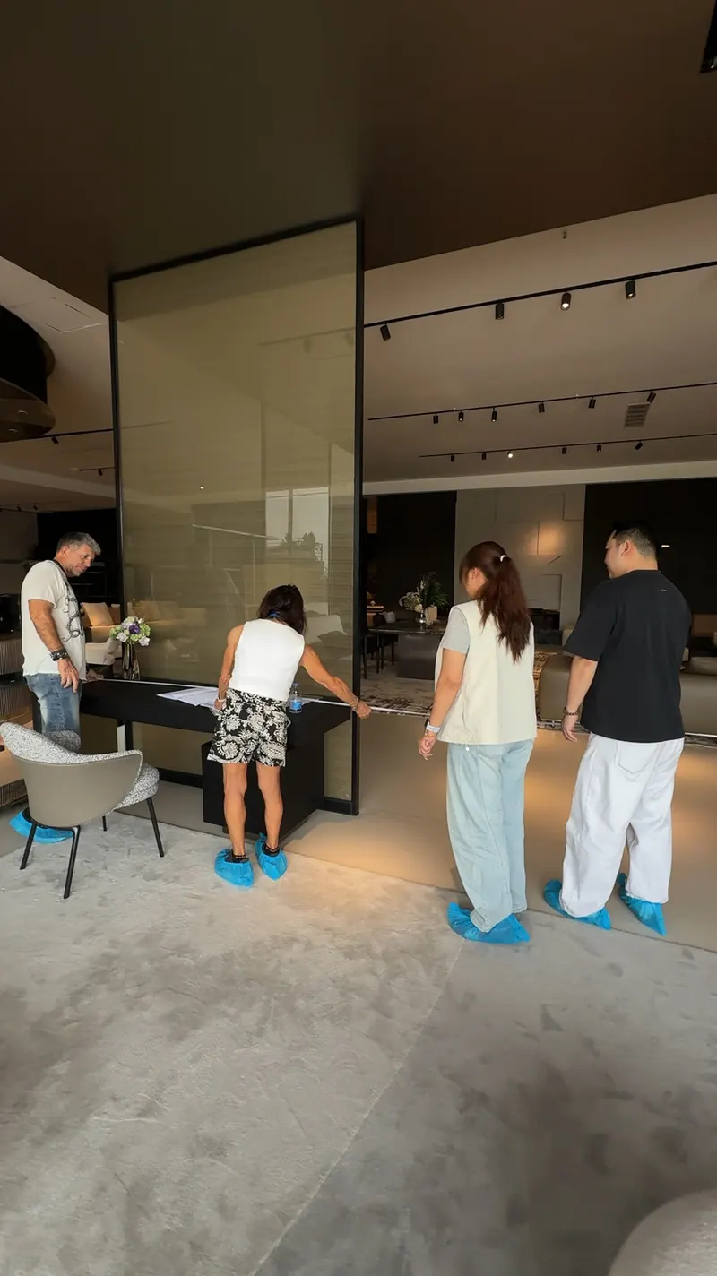 People stand around a dark display table while a tape measure stretches across its top.